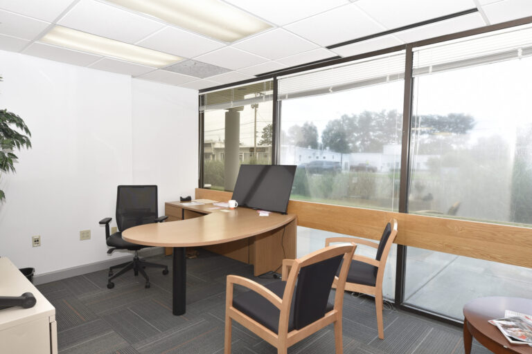 Large, floor to ceiling, windows line the far wall of an office at a office space for rent at 19 Roosevelt Highway, Colchester, VT.